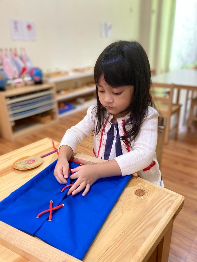 A child practicing lacing on a Montessori dressing frame